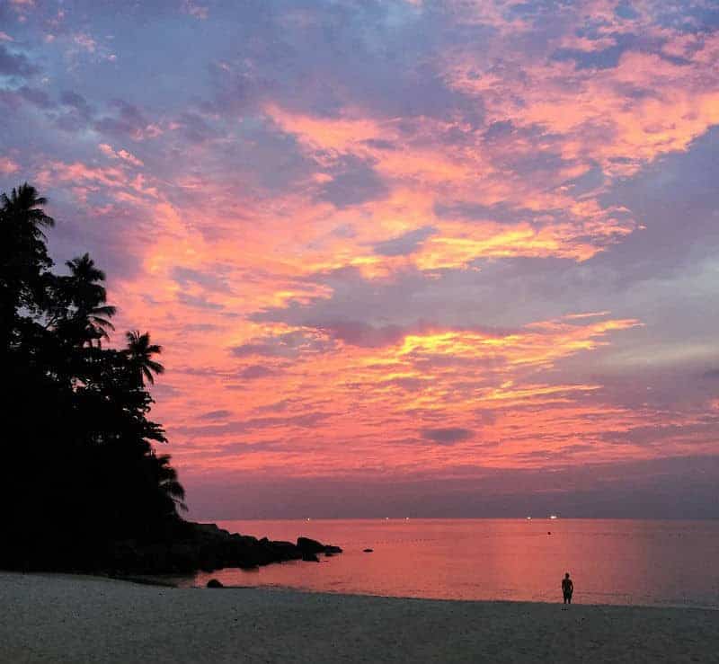 sunset with lone person on beach the surin phuket thailand