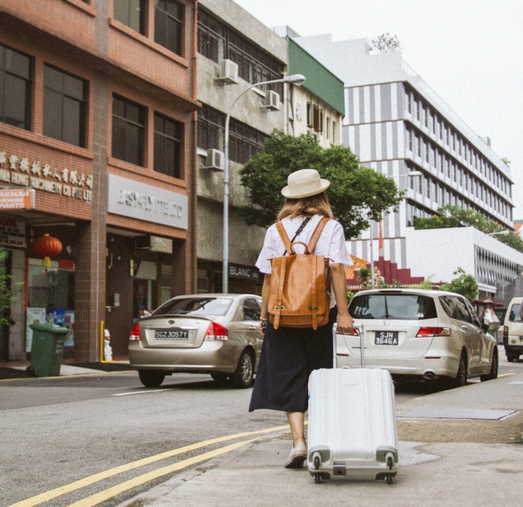 back of woman with hat, backpack and suitase